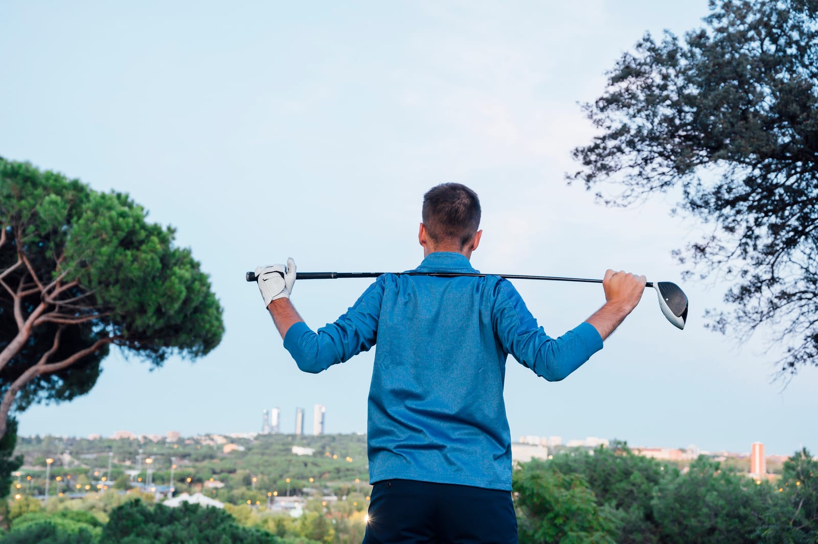 Golfer on the course with a club resting across the back of the shoulders, the setup position for warm-up trunk rotations