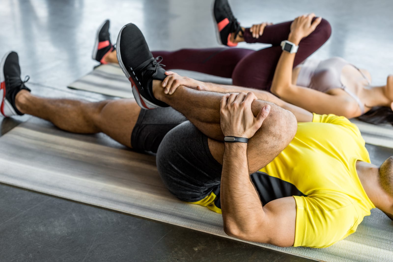 Single knee-to-chest stretch performed on a mat, the kind of simple home stretch prescribed between visits