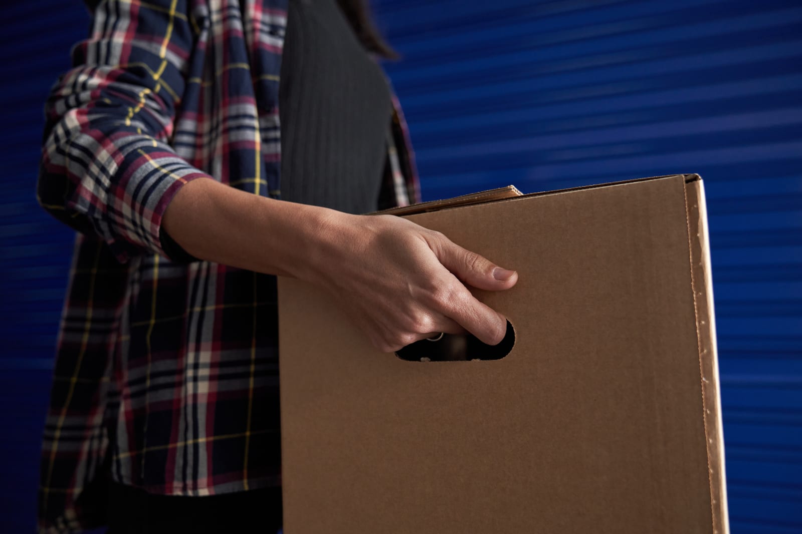 Person carrying a heavy cardboard box, a common way to strain the lower back