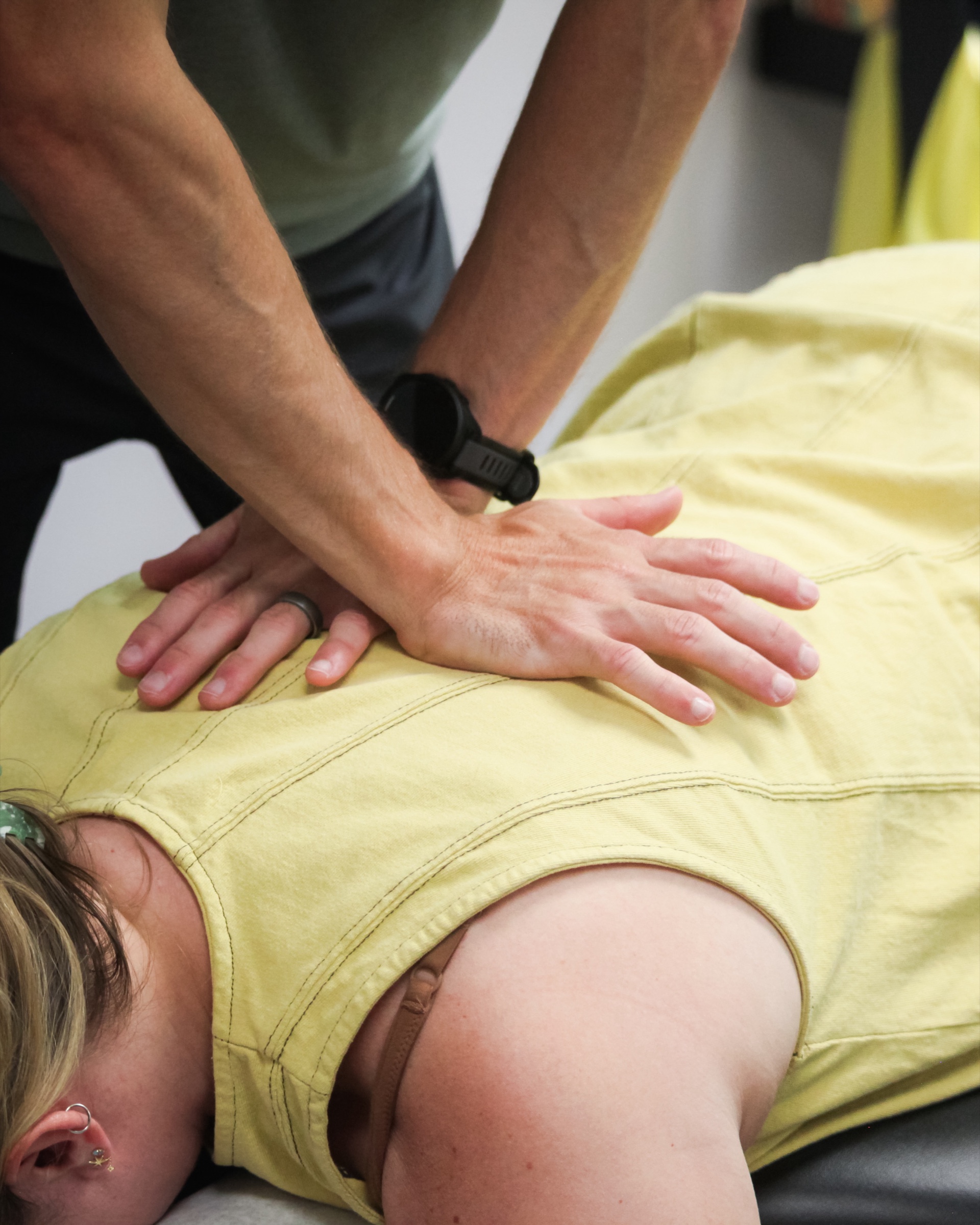 Hands-on assessment of a patient's lower back, where age-related stiffness most often shows up